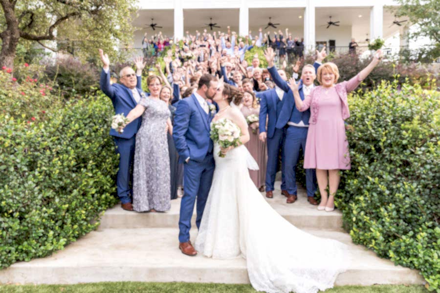 Bride and groom kiss while guests cheer behind them on Kendall Point staircase