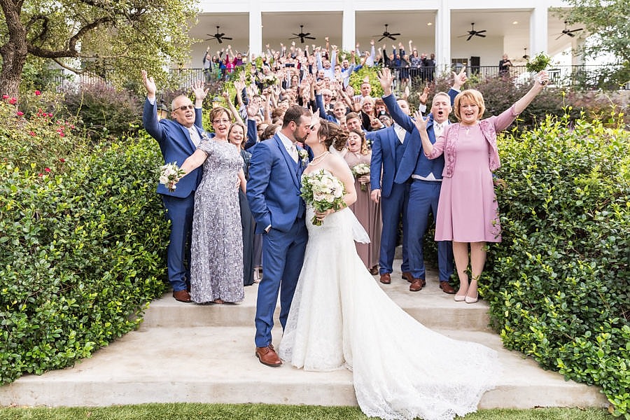 bride and groom kissing with guests cheering behind them