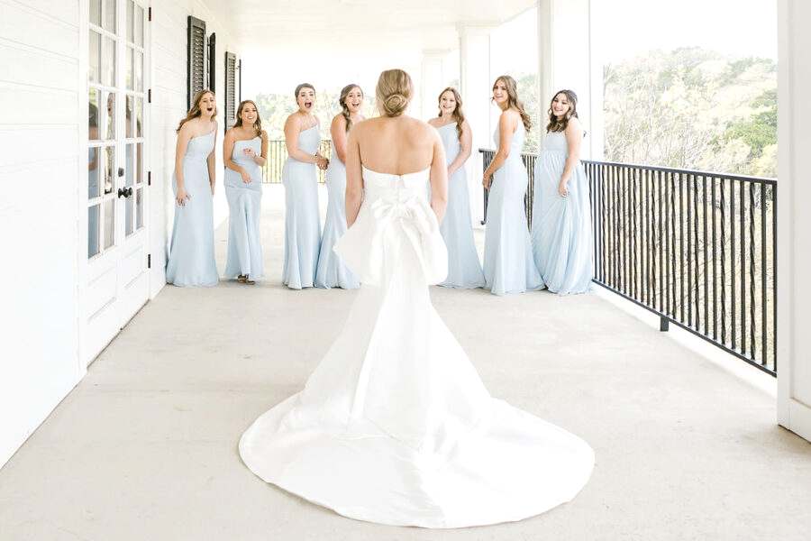 Bridesmaids smiling as they see bride in her wedding dress before wedding ceremony at Kendall Point.