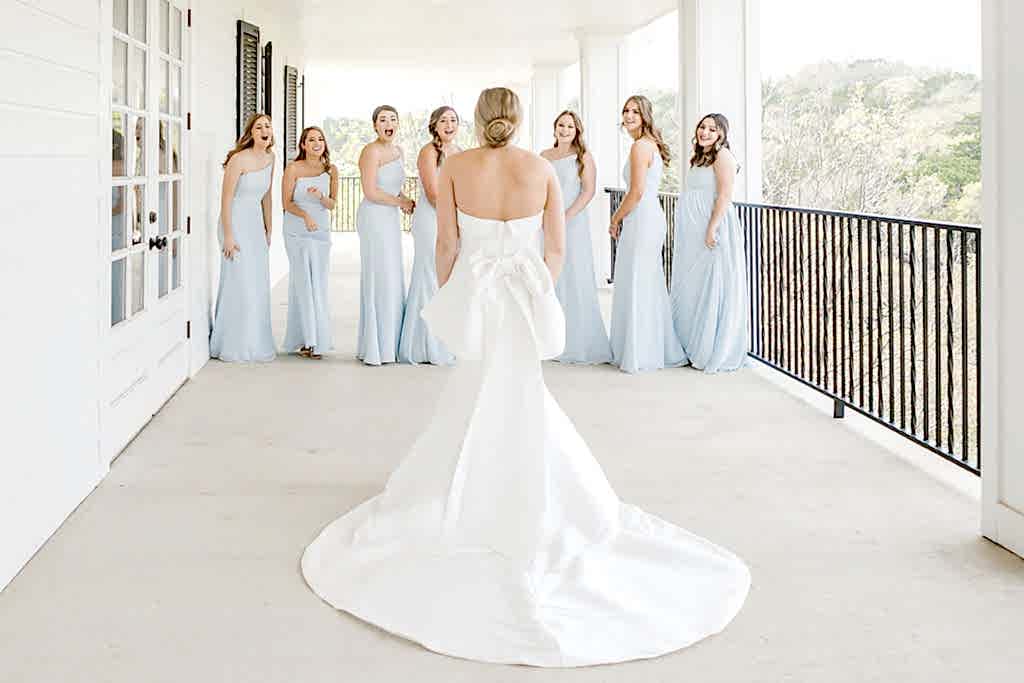 Bridesmaids scream with excitement upon seeing bride in her gown.
