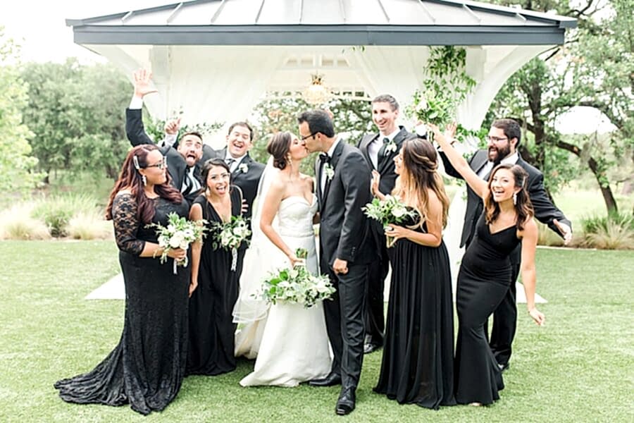 The bride and groom kiss in the front of the Kendall Point gazebo while the bridesmaids and groomsmen cheer.