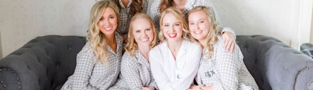 A bride and her bridesmaids pose ont he couch in the bridal suite wearing matching robes.