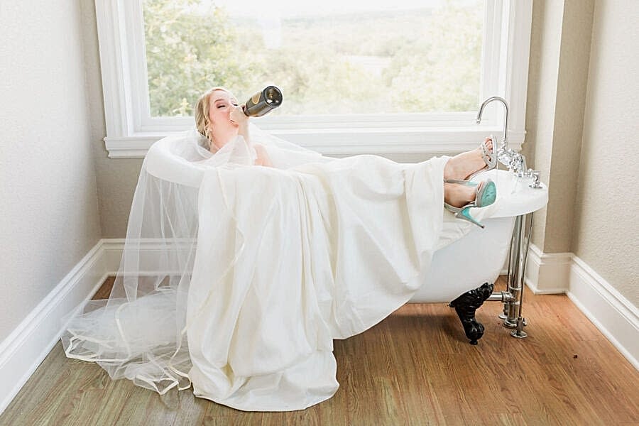 The bride sips champagne in the clawfoot tub in the bridal suite.
