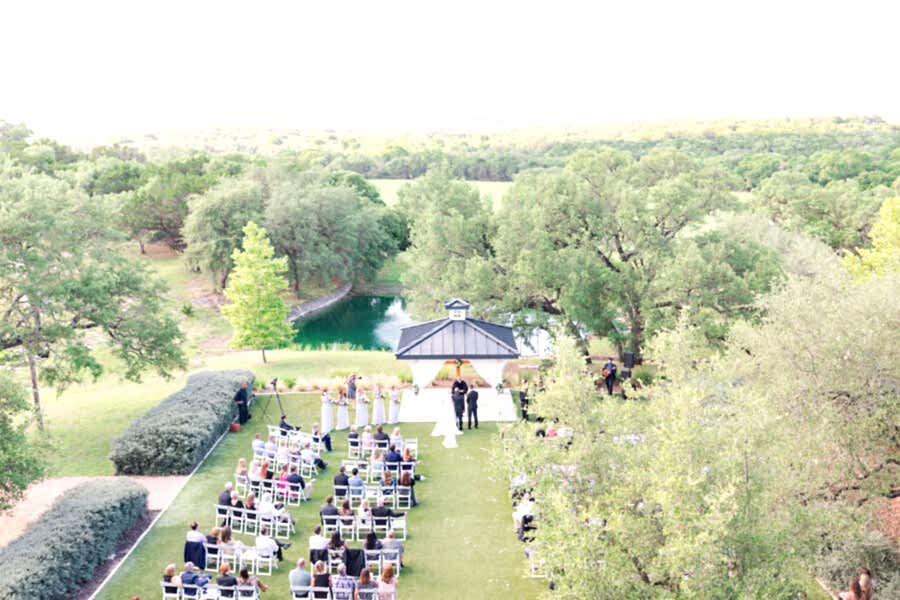 A view of the wedding from the balcony gives a view of the gazebo, lake and surrounding trees.