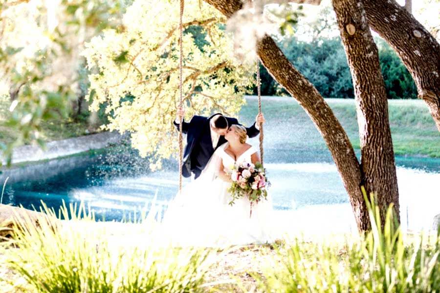 Bride and groom kiss on swing in front of Kendall Point lake.