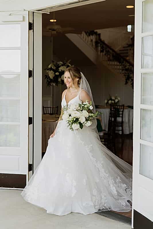 Bride carrying white flowers with green accents at emerald green wedding