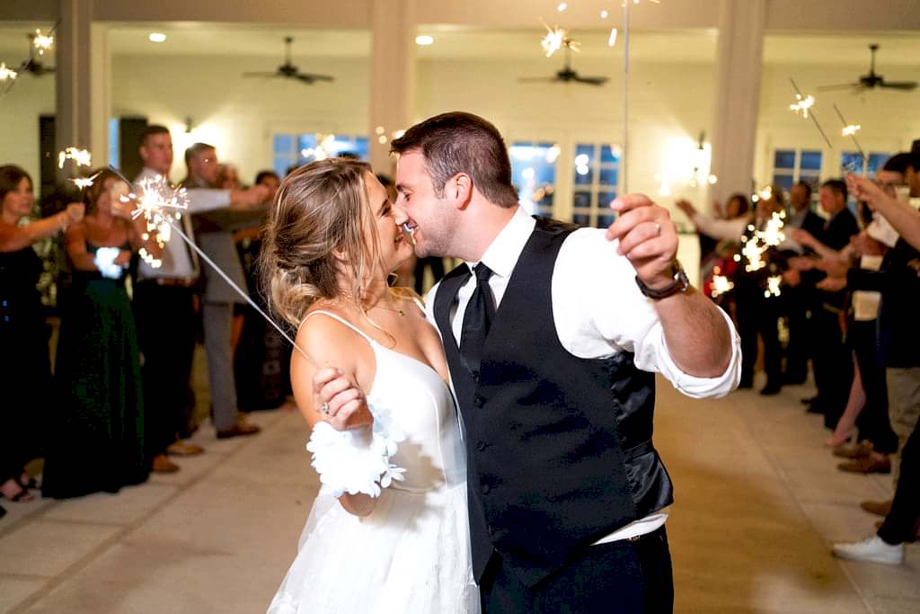 Bride and groom kiss as they exit their wedding under sparklers