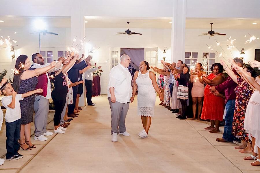 The bride and groom make their exit with the bride wearing a simple but elegant reception dress.