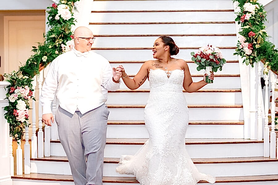 The bride and groom walk down the steps in Kendall Point's ballroom.