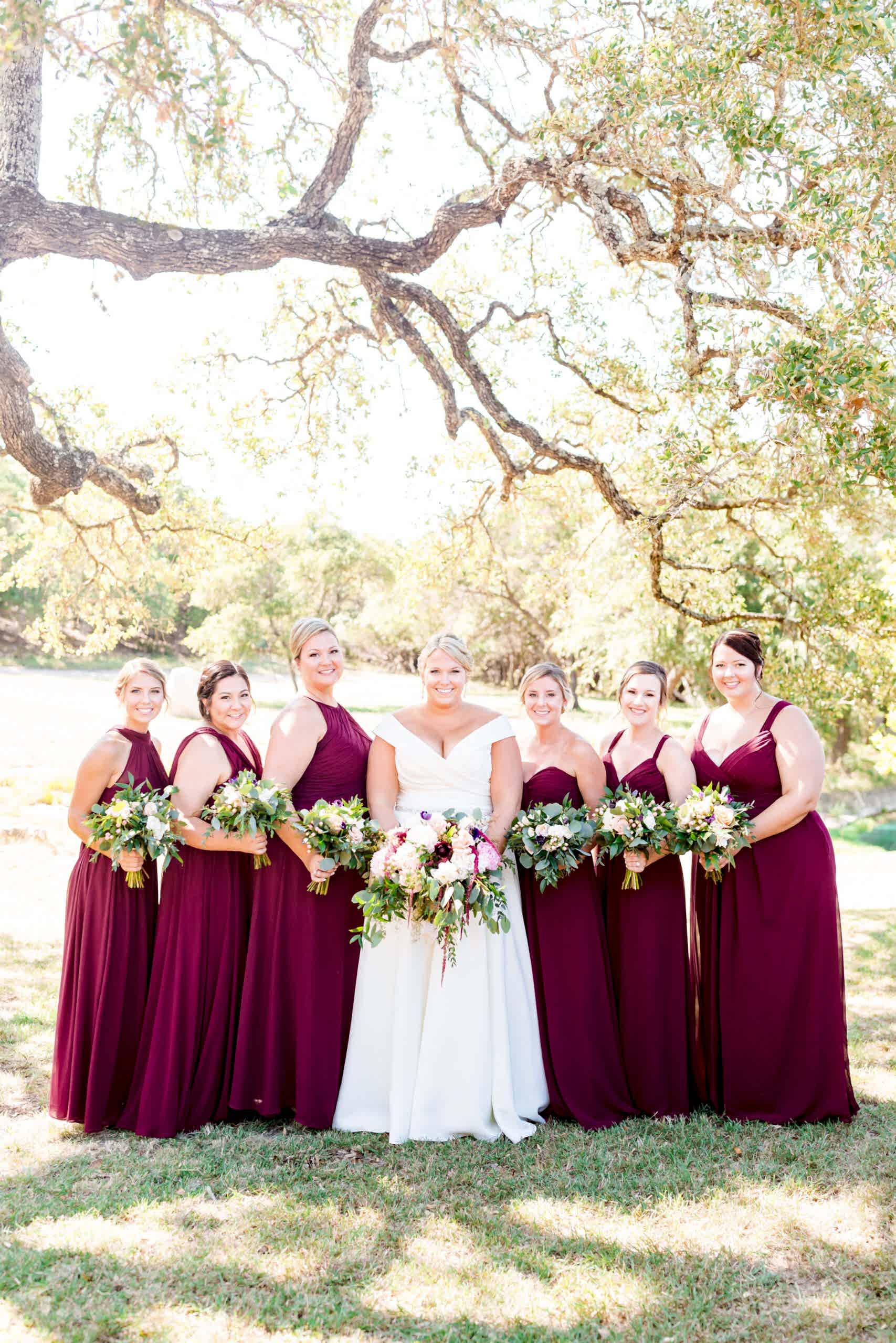 bride flanked by bridesmaids in burgundy dresses