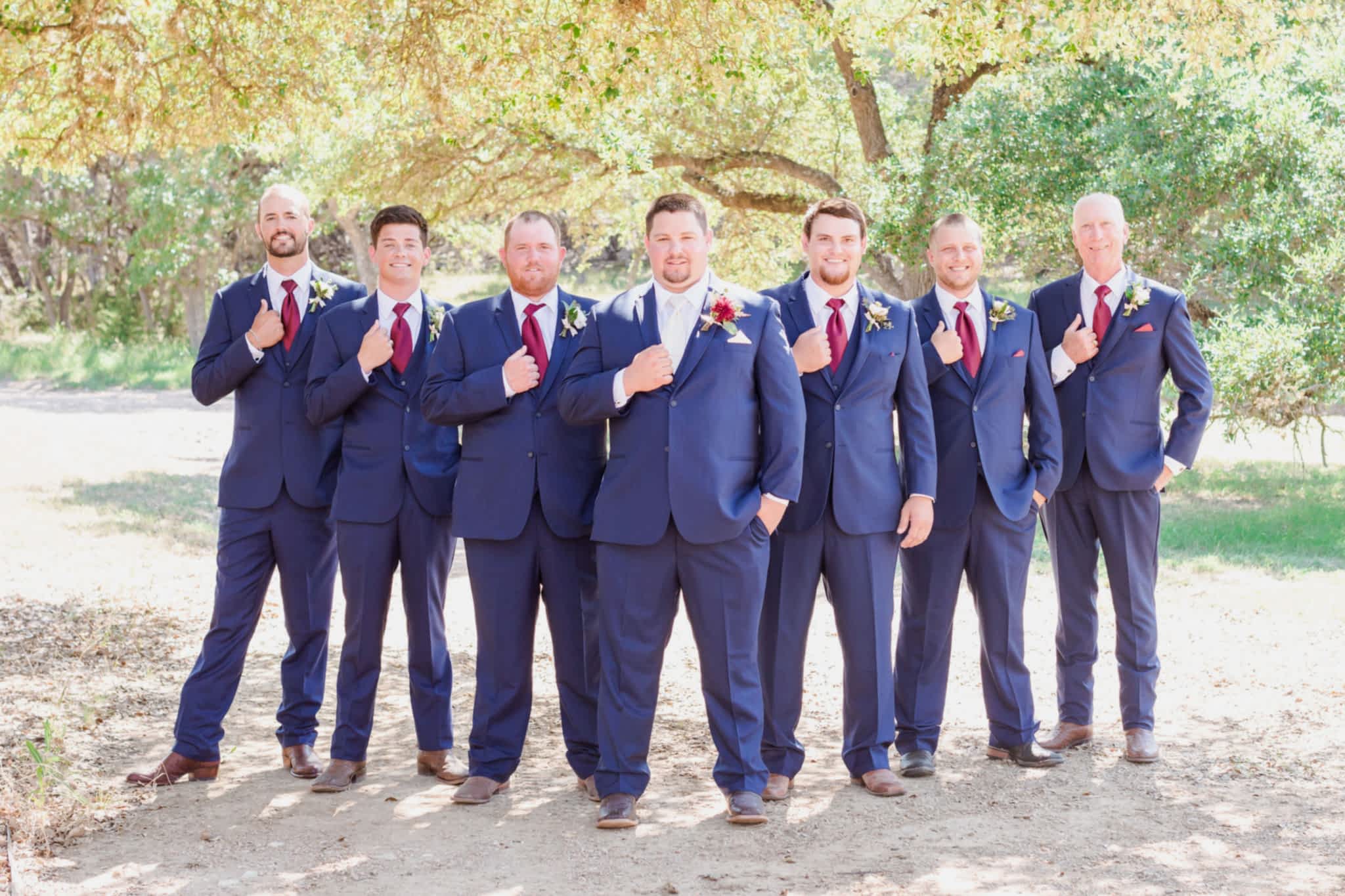 groom and groomsmen in navy suits with burgundy ties.