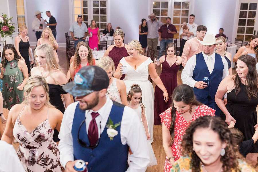 Bride laughing and dancing in the middle of a packed dance floor during wedding reception at Kendall Point.