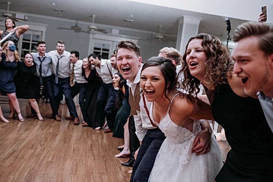 Bride and groom standing and locking arms with their guests and singing along to a song during their wedding reception at Kendall Point.