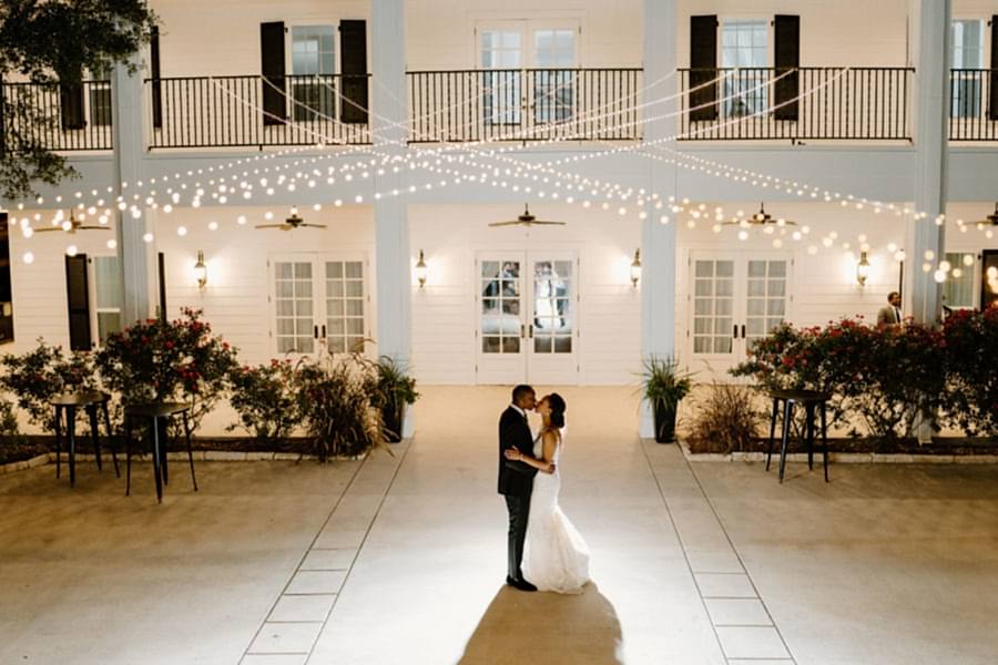 Bride and groom dance outside at Kendall Point under string lights.