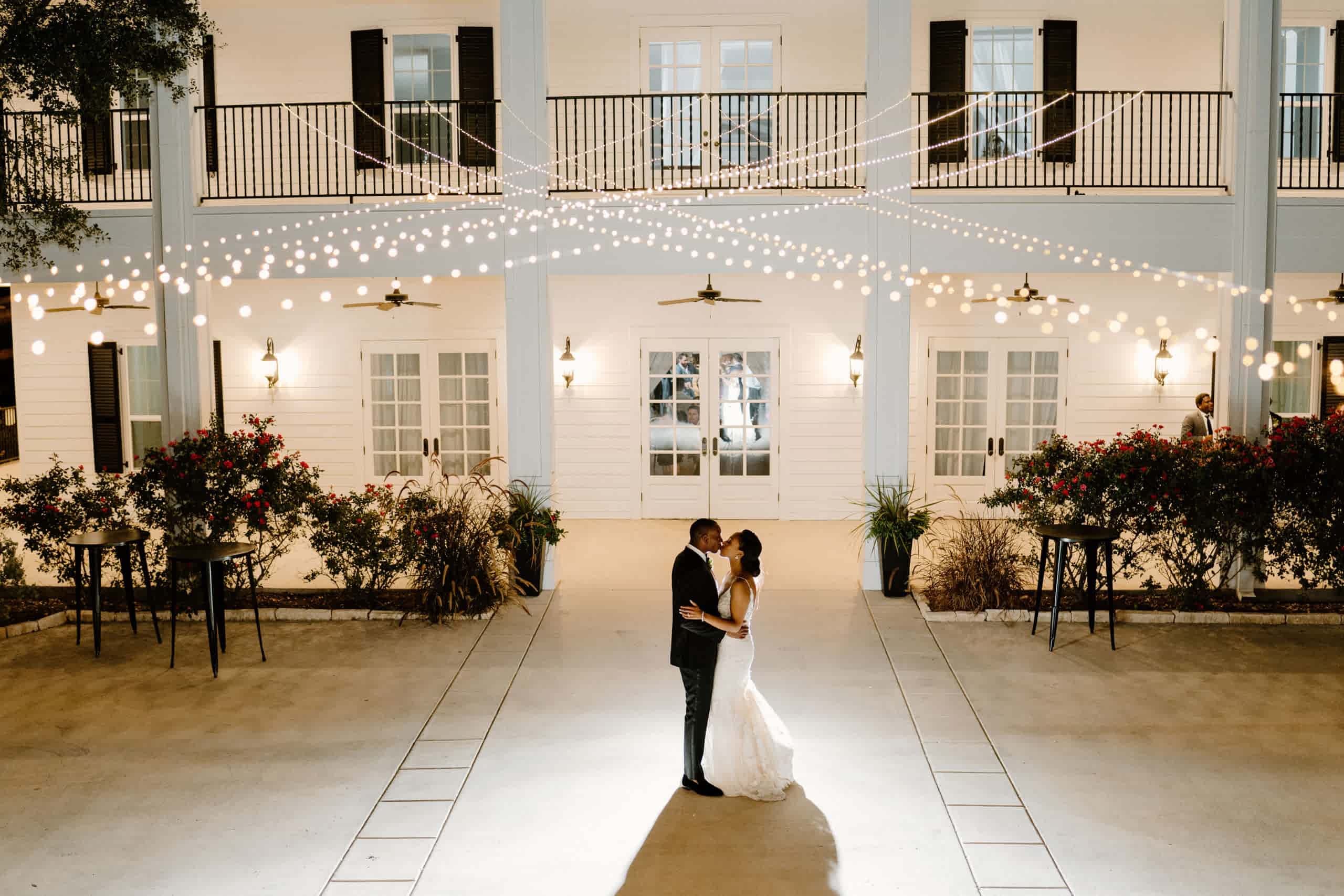 Bride and groom dance outside at Kendall Point under string lights.