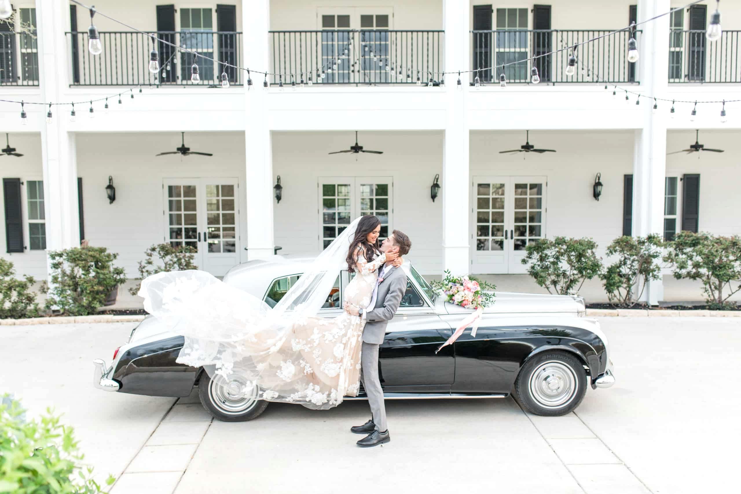 Bride and groom outside of wedding venue next to classic car