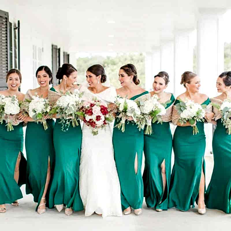 Bride and bridesmaids in green dresses and fur wraps on wrap around porch