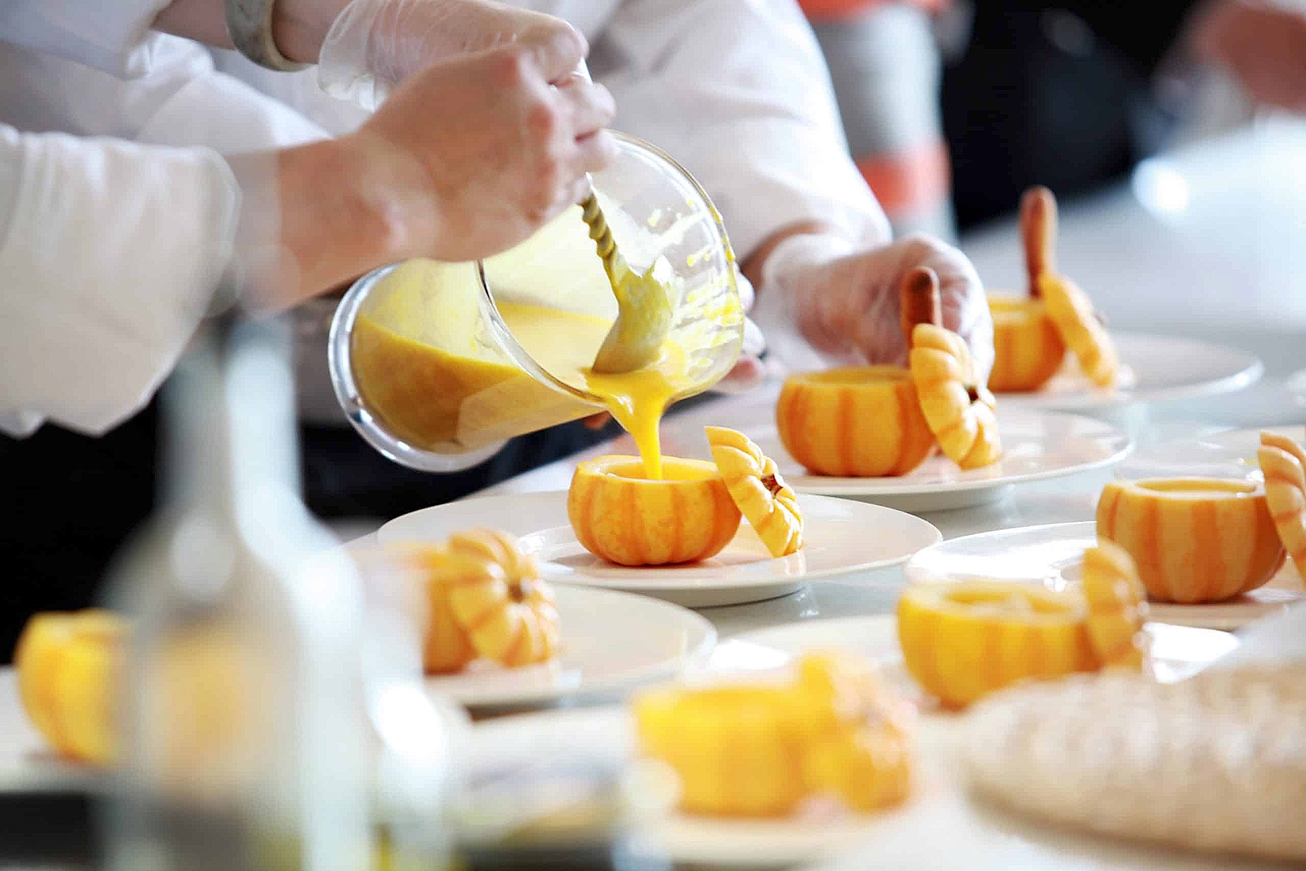 A caterer pours a smoothie into a gourd, a unique food option for a wedding