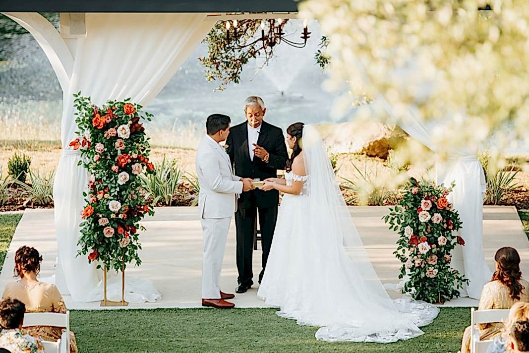 Bride and groom with wedding officiant under gazebo at Kendall Point
