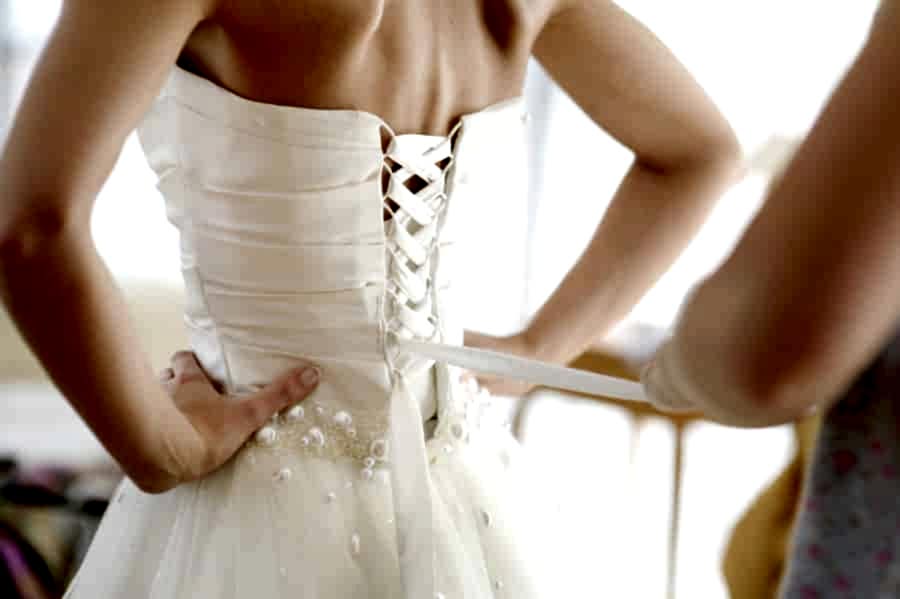 A bride being helped into her corset wedding dress.