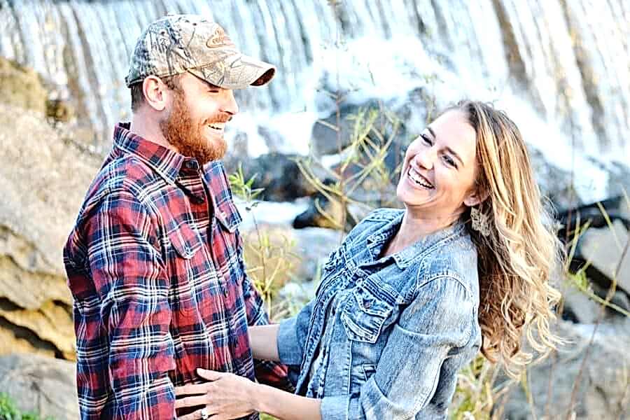 Engaged couple smiling for engagement photos at a waterfall