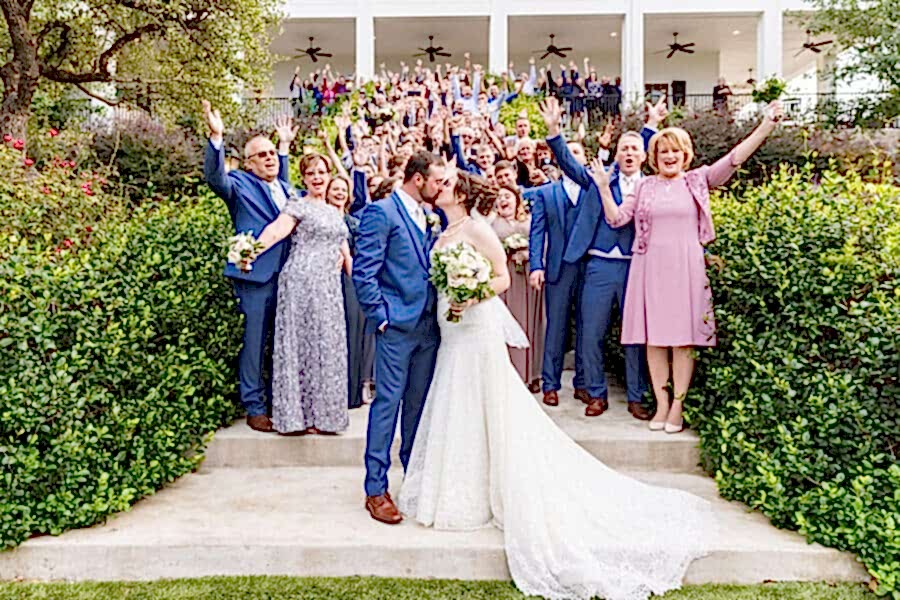 Bride and groom kiss as guests look on and cheer
