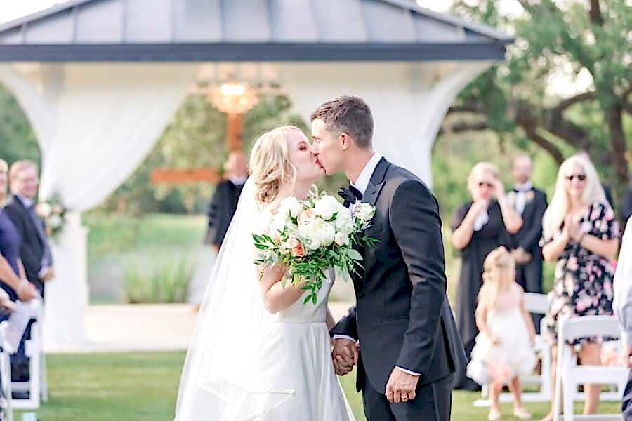 bride and groom kiss at the end of the aisle during kendall point wedding