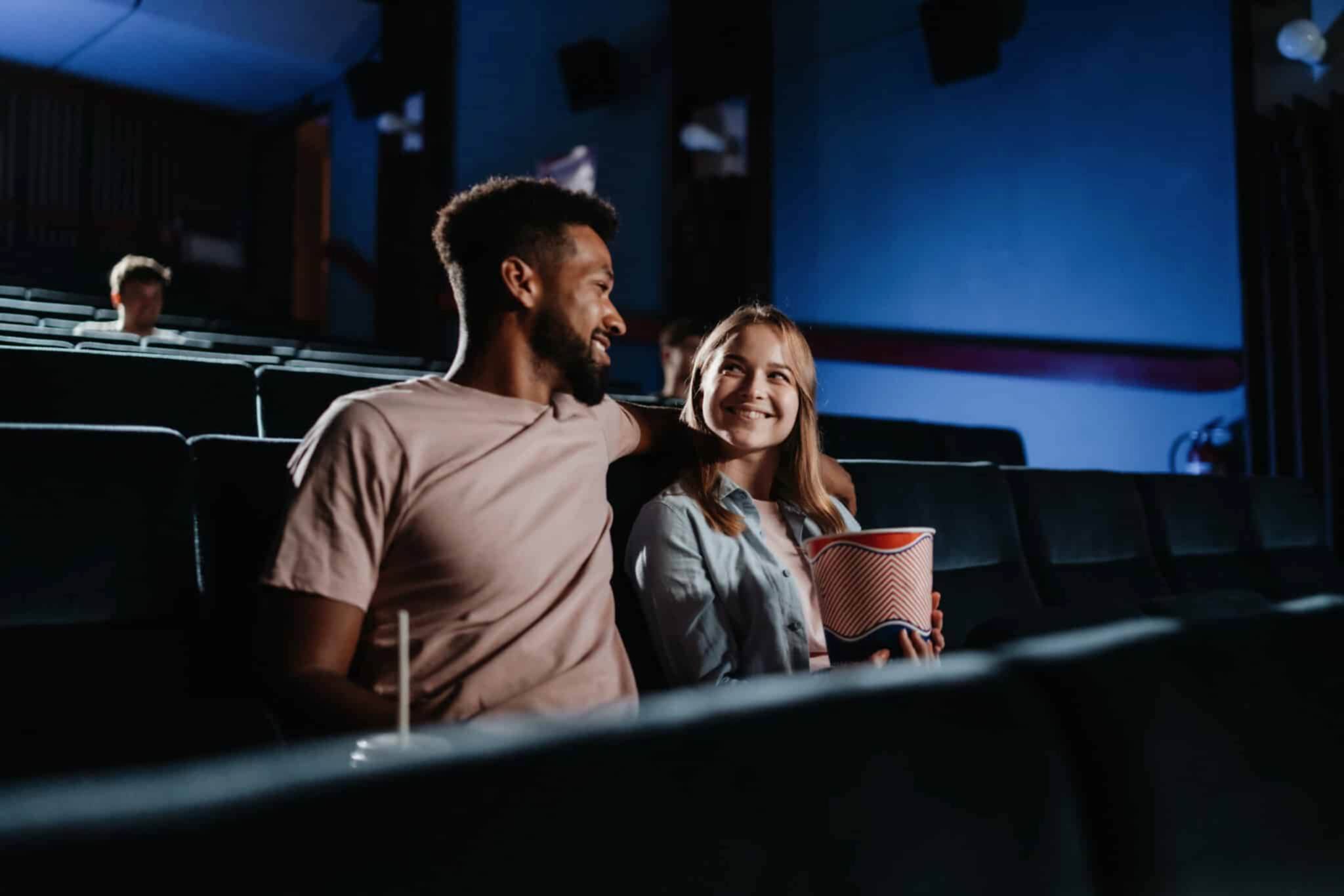 young couple sitting in dark movie theater
