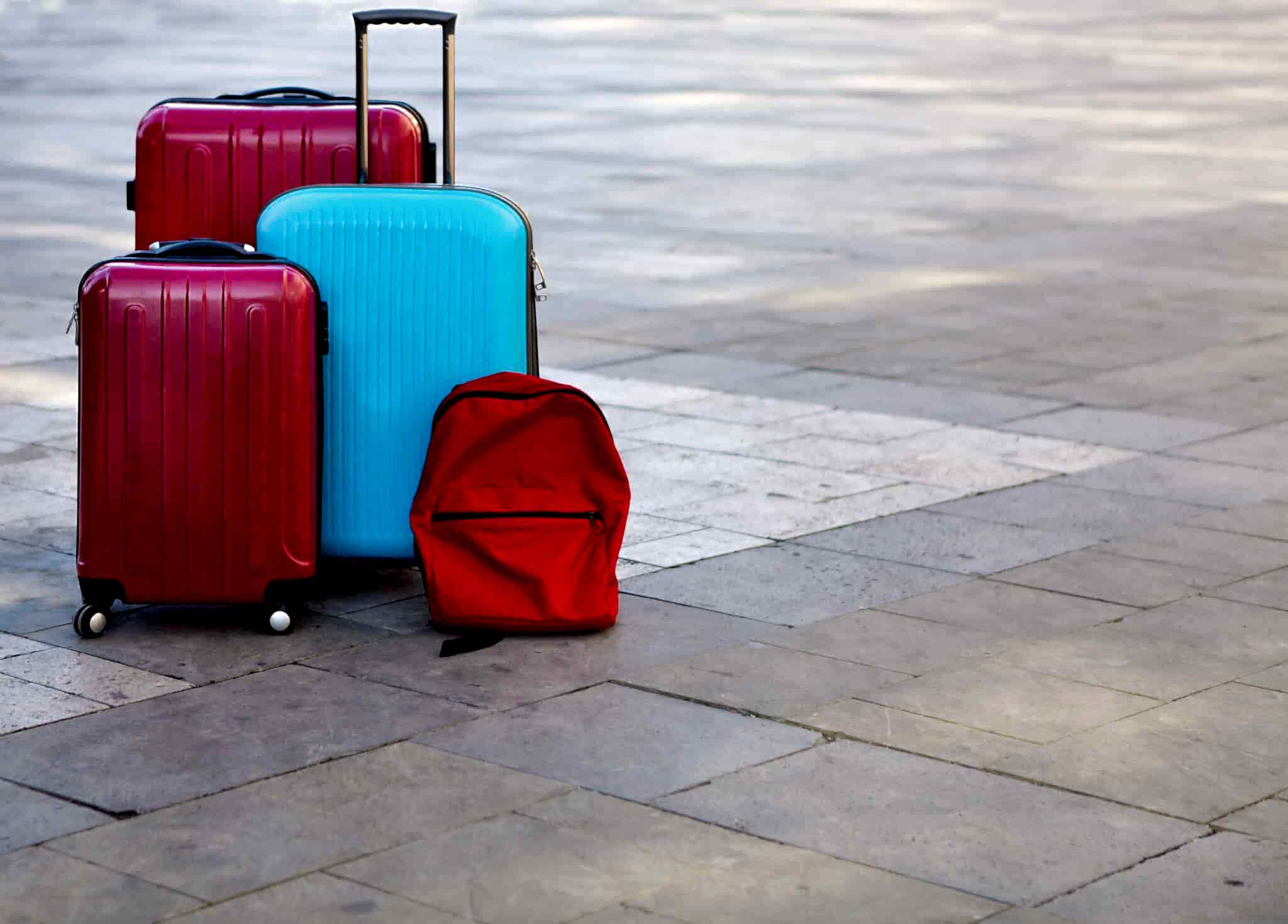 Luggage consisting of three large suitcases and travel backpack on the street. Holiday and travel concept