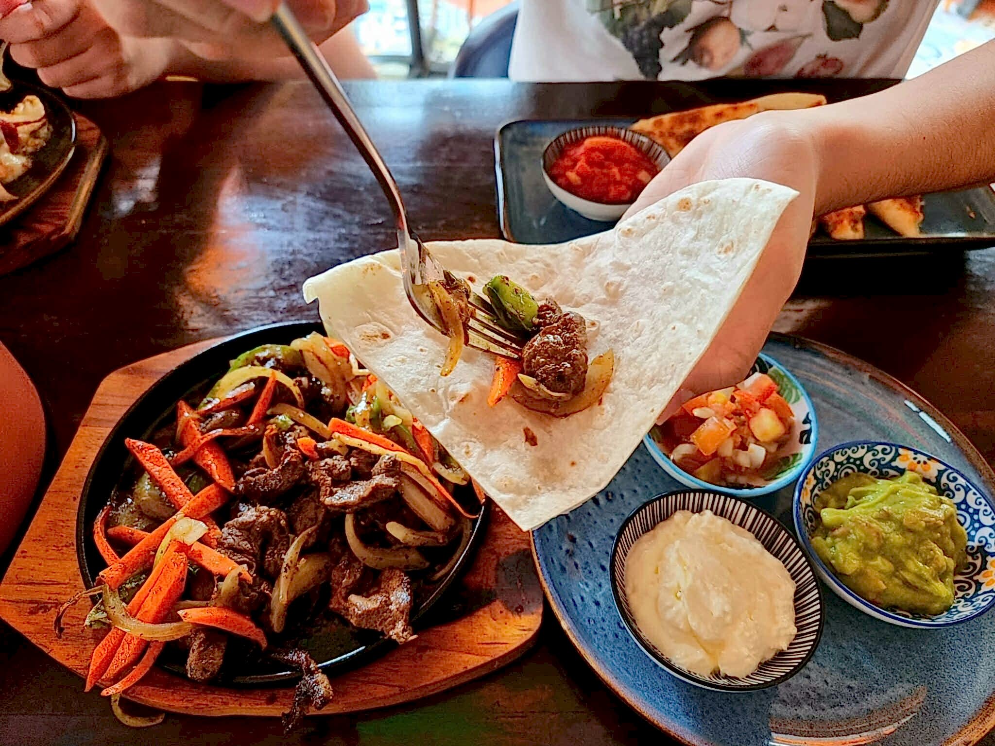 close up of person serving fajitas in restaurant